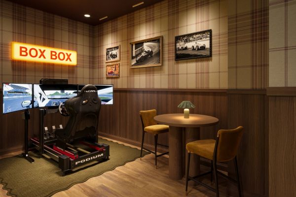 A racing simulator with triple monitors sits next to a small table with chairs.