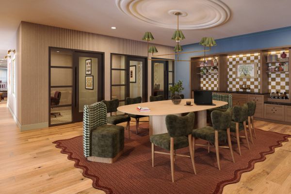 Modern communal workspace with a large oval table, green chairs, checkered wall shelves, and wood flooring.