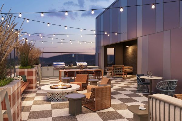 Rooftop terrace with string lights, fire pit, grills, and seating at dusk.