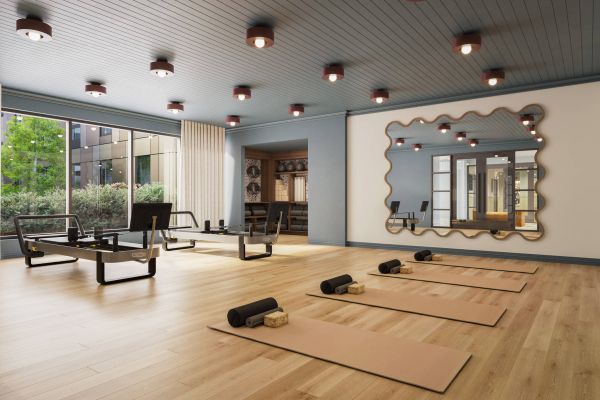 Bright, modern yoga and pilates studio with large windows, wood floors, mats, and fitness equipment.